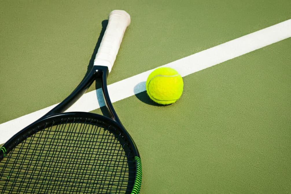 Tennis racket and ball on a green court with white line