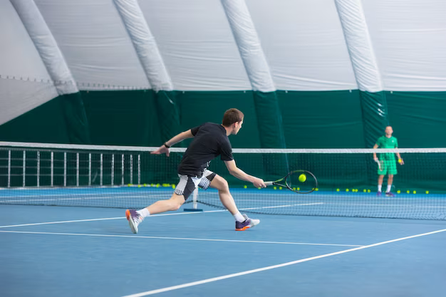 Man on an indoor tennis court with a ball