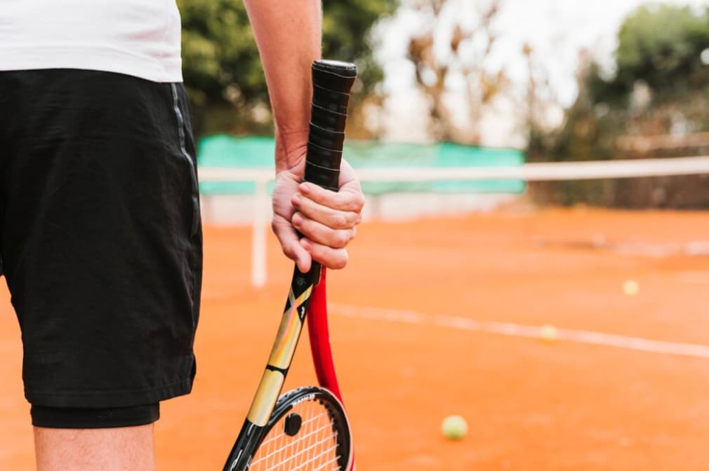 Player holding a tennis racket on a clay court