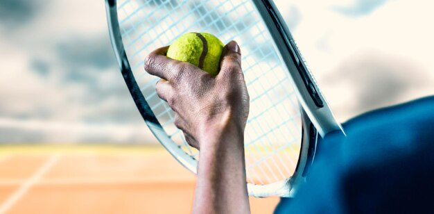 Hand holding tennis ball and racket, close up view