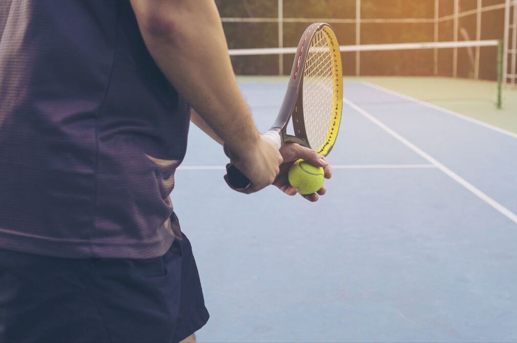 Close up of man holding tennis ball and racquet